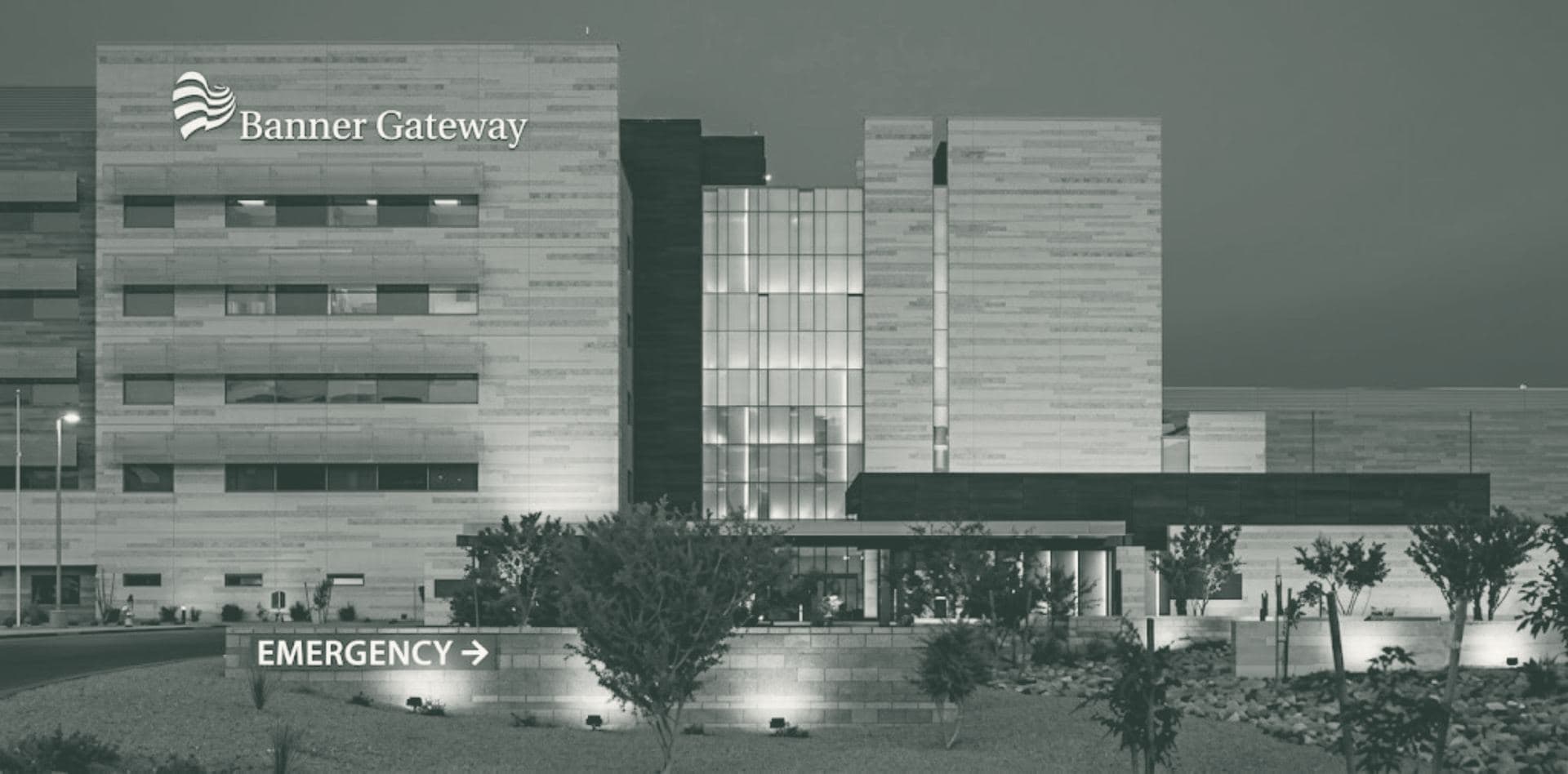 Banner Gateway Medical Center at dusk, with the emergency entrance sign lit